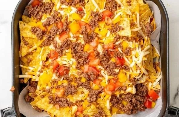 Delicious air fryer nachos topped with cheese, jalapeños, and salsa on a plate.