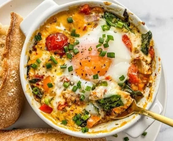 Baked feta eggs with tomatoes and spinach in a baking dish
