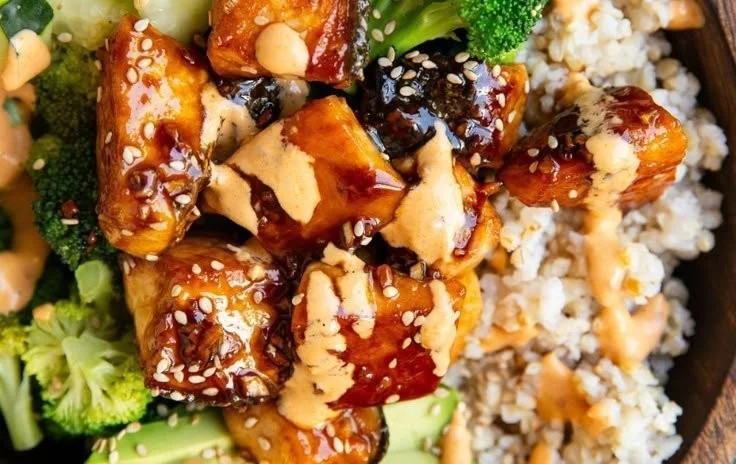 Delicious Bang Bang Salmon Bowls served with fresh vegetables and sauce