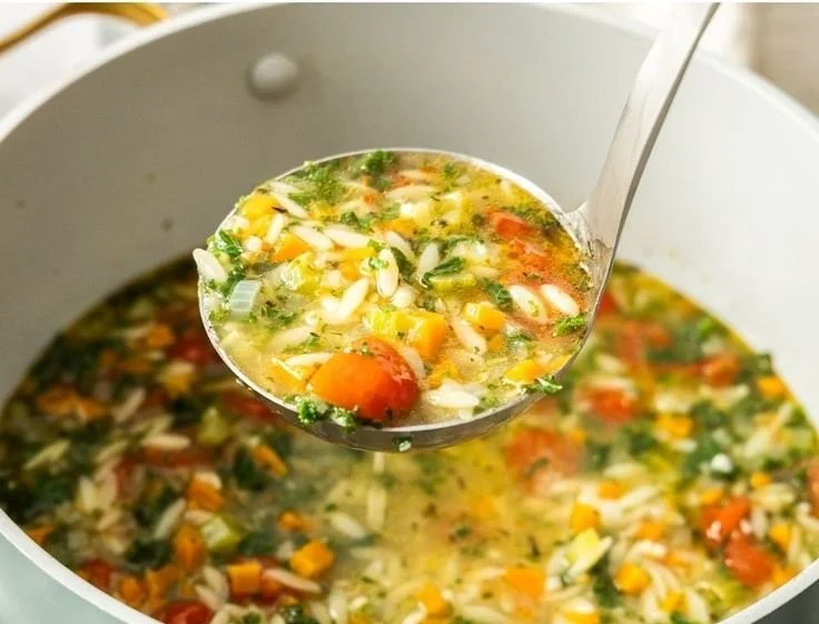 Bowl of Mediterranean-Style Orzo Soup garnished with fresh herbs