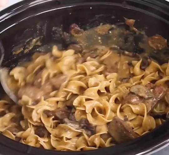 Delicious slow cooker beef stroganoff in a creamy sauce with mushrooms over noodles
